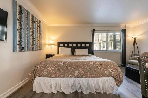 a bedroom with a bed and a chair and a window at Charming Studio Deluxe w/Full Kitchen #115 at Donner Lake Village in Truckee
