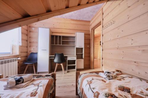 two beds in a room with wooden walls at Grota zbójnicka apartament i pokoje in Gliczarów