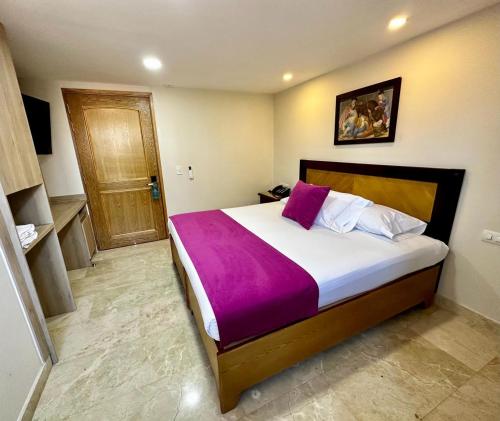 sypialnia z dużym łóżkiem i fioletowym kocem w obiekcie Hotel San Pedro del Fuerte w mieście Medellín