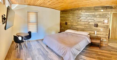 1 dormitorio con 1 cama y pared de madera en Motel Los Robles en Temuco