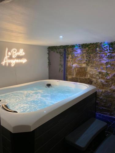a large tub in a bathroom with a stone wall at La bulle Aveyronnaise in Lapanouse