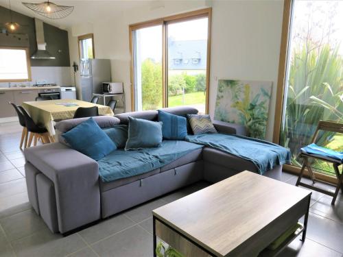 un salon avec un canapé bleu et une table dans l'établissement Maison à Trégastel : WIFI, jardin, terrasse sud, proche plage, calme - FR-1-368-333, à Trégastel
