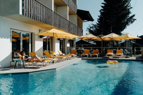 una mujer sentada en una silla junto a una piscina en Hôtel Le Christania, en Bellevaux