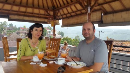 a man and a woman sitting at a table with food at Meme Royak Homestay in Munduk