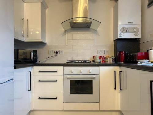 a kitchen with white cabinets and a stove top oven at Elegant Serviced Apartment with Parking in Oxford in Oxford