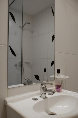 a bathroom sink with a mirror and a bottle of soap at Robinson Alojamientos - Edificio María Gricelda in Ushuaia