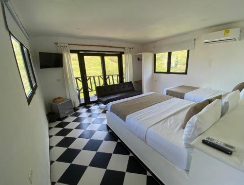 a bedroom with two beds and a checkered floor at Akela Gaira Hotel in Santa Marta