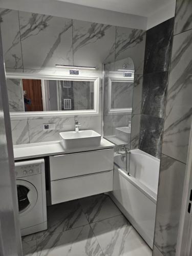 a bathroom with a sink and a washing machine at Apartament Pogodno in Szczecin