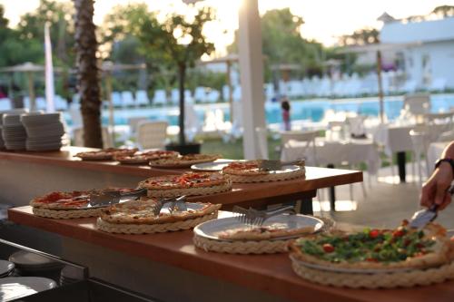- une table avec plusieurs pizzas à côté de la piscine dans l'établissement Resort Acqua di Venere, à Paestum