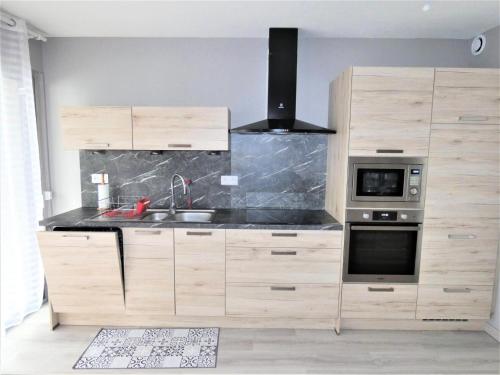 une cuisine avec des armoires en bois, un évier et une cuisinière dans l'établissement Résidence L'elvire - Très fonctionnel logement dans quartier animé ! MAE-6604, à Aix-les-Bains