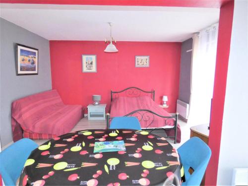 Cette chambre aux murs rouges comprend une table et un lit. dans l'établissement Résidence L'elvire - Très fonctionnel logement dans quartier animé ! MAE-6604, à Aix-les-Bains