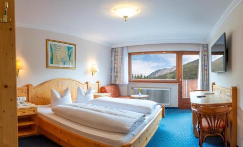 ein Hotelzimmer mit einem Bett, einem Schreibtisch und einem Fenster in der Unterkunft Hotel Brunella in Vandans