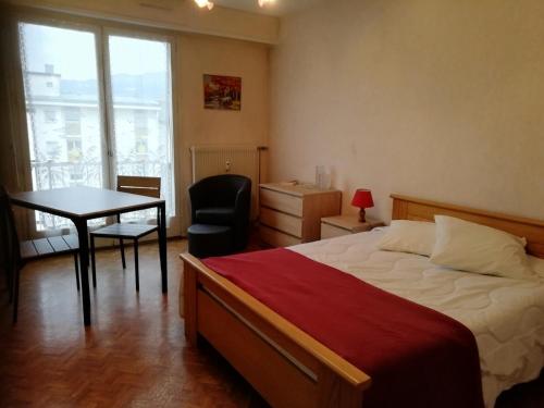 une chambre avec un lit et une table avec une chaise dans l'établissement Résidence Le Jasmin - Paisible logement , quartier tranquille ! MAE-6724, à Aix-les-Bains