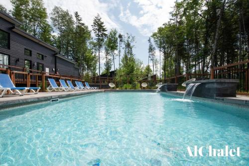 uma piscina com cadeiras e uma cascata em Beaulieu - vue boisé spa sauna em Pont-Rouge