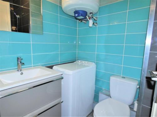 La salle de bains est pourvue de carrelage bleu, de toilettes et d'un lavabo. dans l'établissement Résidence Les Roseaux - Agréable 2 pièces au calme au bord du lac ! MAE-6784, à Aix-les-Bains