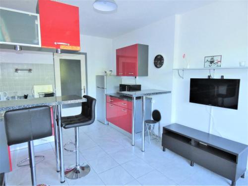 Il comprend une cuisine avec des placards rouges et une télévision. dans l'établissement Résidence Les Roseaux - Agréable 2 pièces au calme au bord du lac ! MAE-6784, à Aix-les-Bains