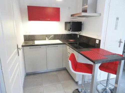 une petite cuisine avec un comptoir et des chaises rouges dans l'établissement Résidence Le Bachelard - Logement hyper centre, moderne ! MAE-6814, à Aix-les-Bains