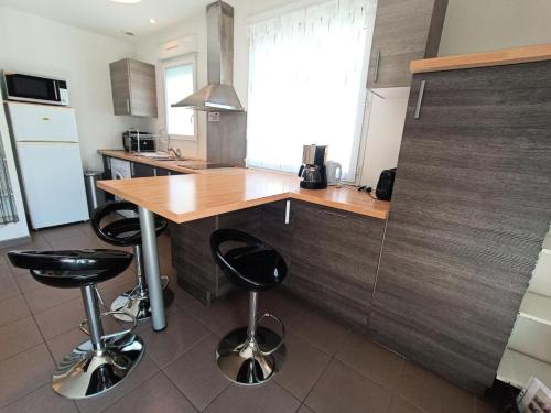 une cuisine avec un comptoir en bois et deux tabourets dans l'établissement Residence Immocite - Agréable logement avec sa grande agréable terrasse et terrain clos ! MAE-6694, à Aix-les-Bains