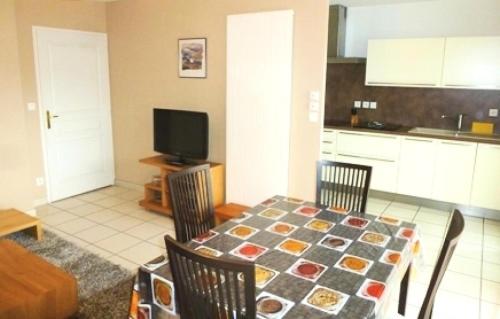 une cuisine avec une table et des chaises ainsi qu'une télévision dans l'établissement Residence L'albizia - Moderne et fonctionnel au coeur de la ville d'Aix les Bains ! MAE-6754, à Aix-les-Bains
