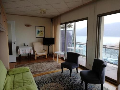 d'un salon avec un canapé et des chaises ainsi que d'un balcon. dans l'établissement Résidence Les Belles Rives E - Vue magnifique et imprenable sur le lac du Bourget ! MAE-6774, à Aix-les-Bains