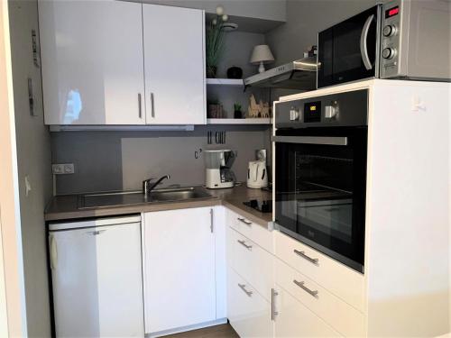 La cuisine est équipée de placards blancs et d'un four micro-ondes noir. dans l'établissement Résidence L'elvire - Chaleureux Studio dans quartier animé ! MAE-6964, à Aix-les-Bains