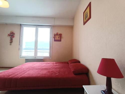 - une chambre avec un lit rouge et une fenêtre dans l'établissement Résidence Le Chateau Durieux 4 - Très mignon studio et très calme ! MAE-6984, à Aix-les-Bains