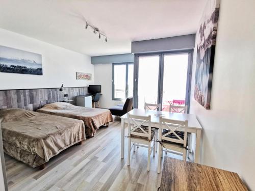 Cette chambre comprend deux lits, un bureau et une table. dans l'établissement Résidence Le Chateau Durieux 4 - Coup de coeur pour ce petit studio entièrement relooké ! MAE-7184, à Aix-les-Bains