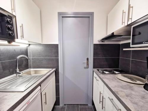 une petite cuisine avec un évier et une porte. dans l'établissement Résidence Le Chateau Durieux 4 - Coup de coeur pour ce petit studio entièrement relooké ! MAE-7184, à Aix-les-Bains