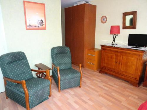 Cette chambre comprend deux chaises, un bureau et une télévision. dans l'établissement Résidence Le Chateau Durieux 3 - Au calme avec vue dégagée, studio 2 personnes ! MAE-7334, à Aix-les-Bains