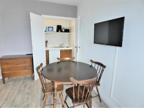 une table à manger avec des chaises et une télévision murale. dans l'établissement Résidence Le Chateau Durieux 3 - Agréable studio, bien situé ! MAE-7574, à Aix-les-Bains