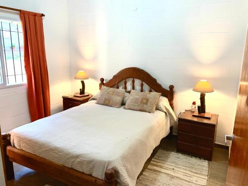 a bedroom with a bed with two lamps on tables at Cabaña Clarita La Florida in La Florida