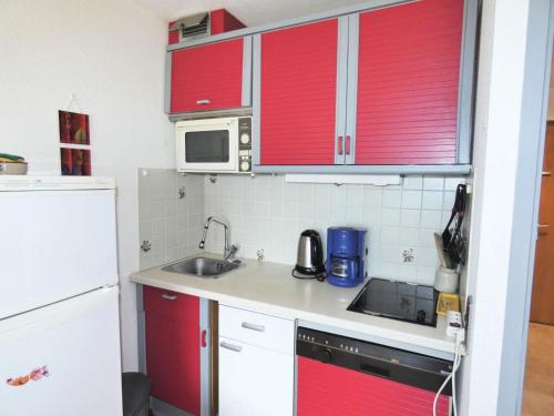 une petite cuisine avec des armoires rouges et un évier dans l'établissement Résidence Les Hirondelles - Idéal pour les vacances, studio pour 4 personnes ! MAE-7854, à Aix-les-Bains