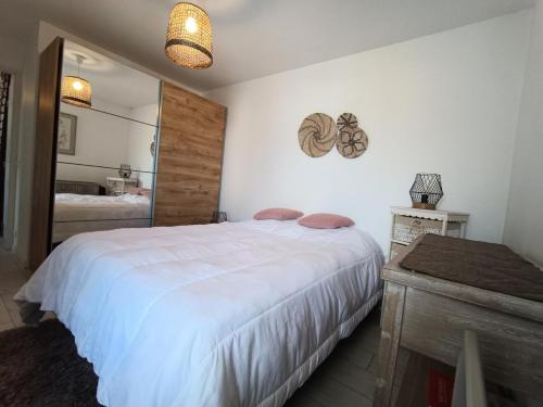 une chambre avec un grand lit blanc et un miroir dans l'établissement Résidence La Cerisaie - Coquet pour ce joli 2 pièces ! MAE-7004, à Aix-les-Bains