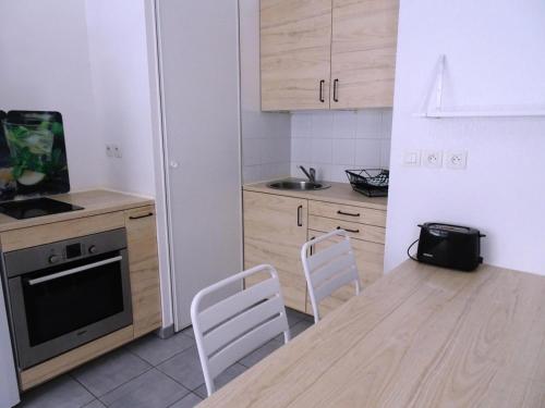 - une cuisine avec une table en bois et des chaises blanches dans l'établissement Residence Amaryllis - Agréable logement au coeur de la ville ! MAE-8144, à Aix-les-Bains