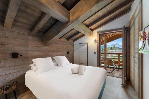 1 cama blanca grande en una habitación con paredes de madera. en Résidence Ksar B - 4 Pièces pour 6 Personnes 164, en Megève