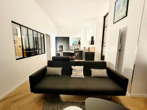 - un salon avec un canapé noir et des oreillers dans l'établissement Résidence Le Bernascon - Chaleureux appartement dans ancien palace ! MAE-8154, à Aix-les-Bains