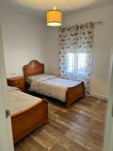 1 dormitorio con 2 camas y ventana en La Casita Rural, en La Carlota