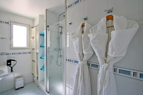 La salle de bains est pourvue de serviettes blanches accrochées au mur. dans l'établissement Villa Du Golf De La Grande Motte - Maisons & Villas pour 12 Perso 044, à La Grande Motte