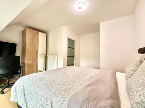 a white bedroom with a bed and a desk at Il Casolare in Beersel