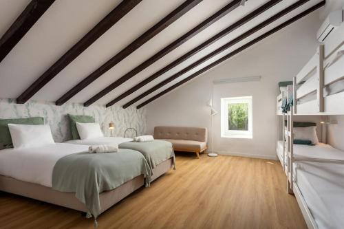 two beds in a room with white walls and wooden floors at Casa da Azenha - Quinta do Boição - Private pool in Bucelas