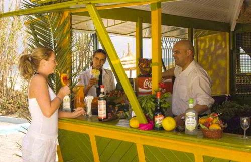 a woman standing in front of a bar with drinks at Monarque El Fatimi Mahdia in Mahdia