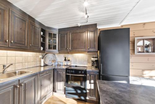 a kitchen with wooden cabinets and a black refrigerator at Hytte Stryn skisenter in Stryn