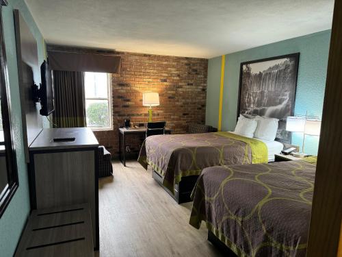 ブライズビルにあるSuper 8 by Wyndham Blythevilleのベッド2台とデスクが備わるホテルルームです。