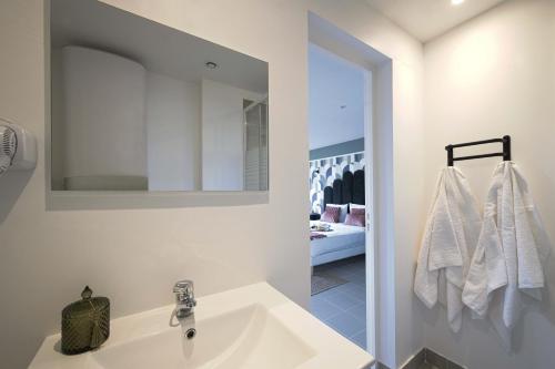 Baño blanco con lavabo y espejo en Modern bright Apartment in appart'hotel en Saint-Maur-des-Fossés