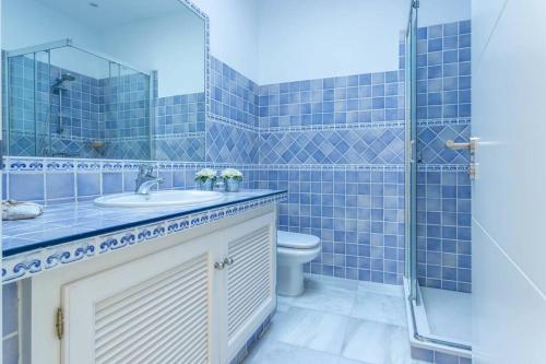 een blauw betegelde badkamer met een wastafel en een toilet bij Villaflair - Marbella Sea View in Marbella