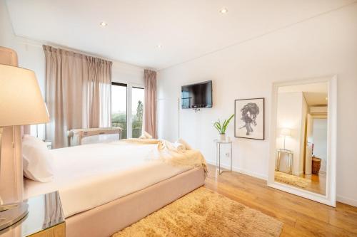 um quarto branco com uma cama grande e um espelho em GuestReady - Comfortable Getaway in Sesimbra em Sesimbra