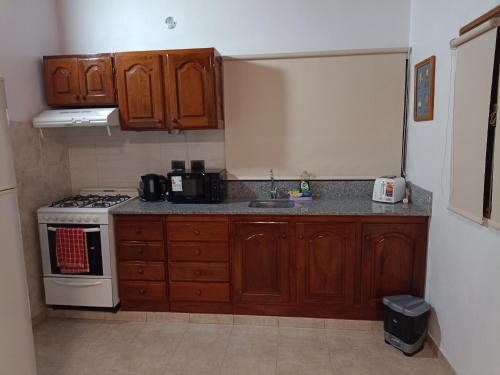 uma cozinha com armários de madeira e um forno com placa de fogão em Las Casuarinas em San José