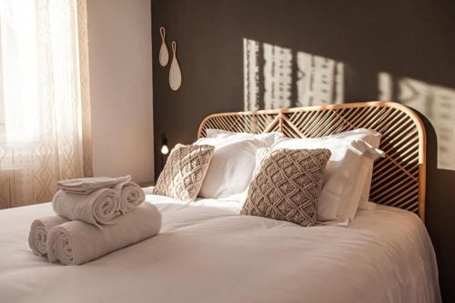un letto bianco con cuscini e asciugamani di L'Exotique - Gare/centre, lumineux, spacieux, neuf a Châteauroux