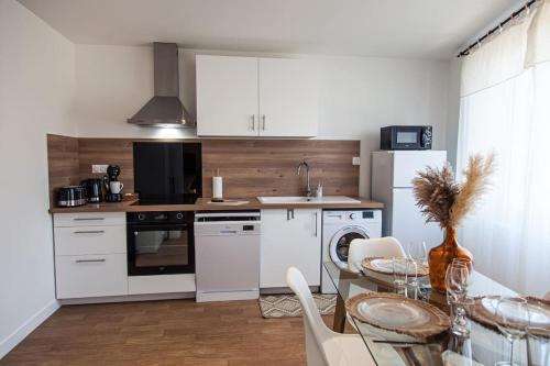 a kitchen with white appliances and a table with chairs at L'Exotique - Gare/centre, lumineux, spacieux, neuf in Châteauroux