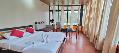 1 dormitorio con 1 cama blanca grande con almohadas rojas en Estet stay with pool en Madikeri